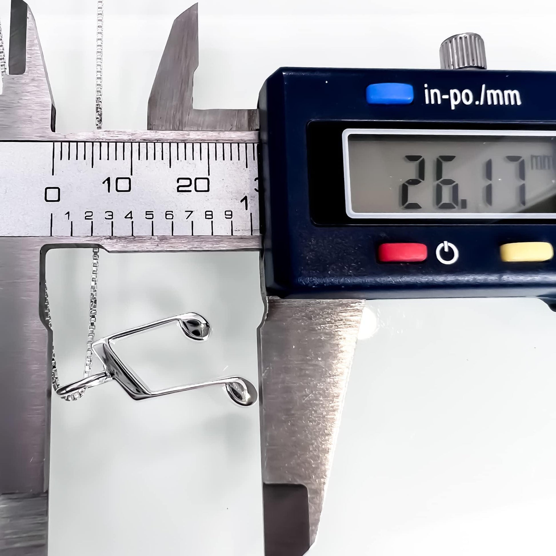 A digital caliper is being used to measure the size of a silver chain.