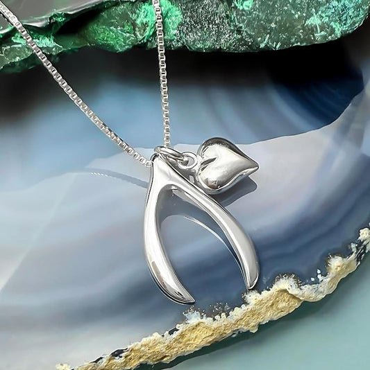 A silver necklace with a pendant featuring a heart-shaped charm is displayed against a blue and green background.