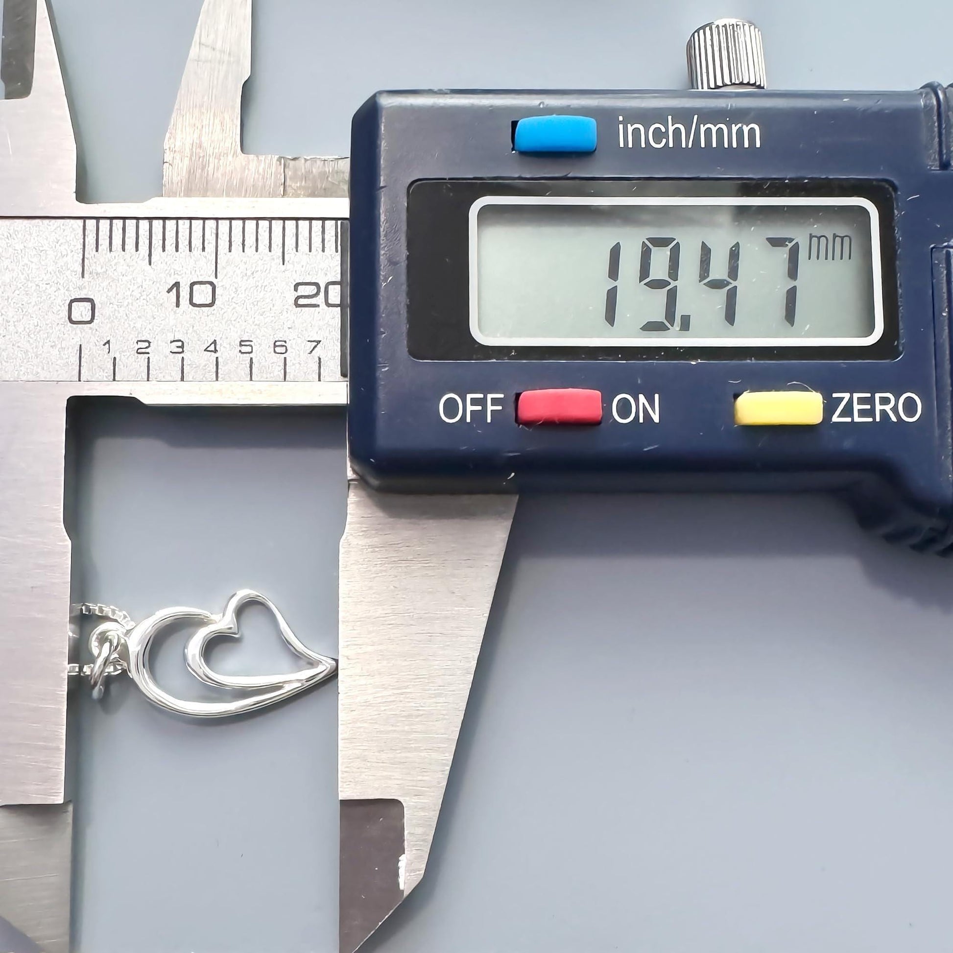 A digital caliper is being used to measure the size of a silver necklace chain.