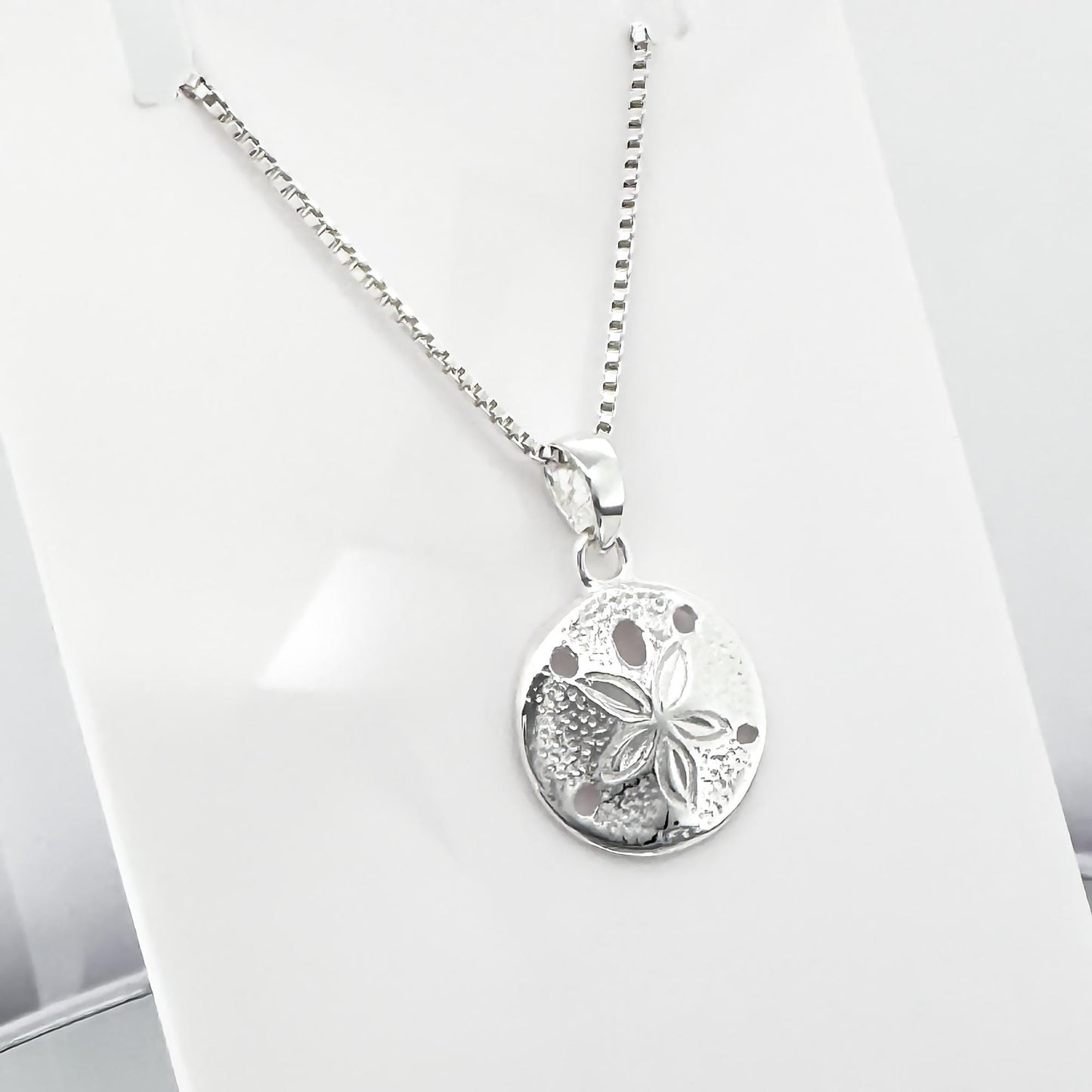 A silver necklace with a round pendant featuring a flower design.