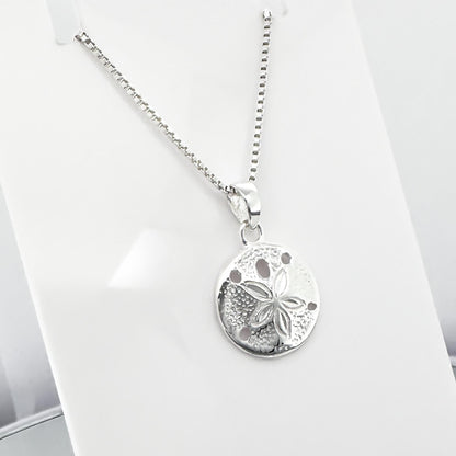A silver necklace with a round pendant featuring a flower design.