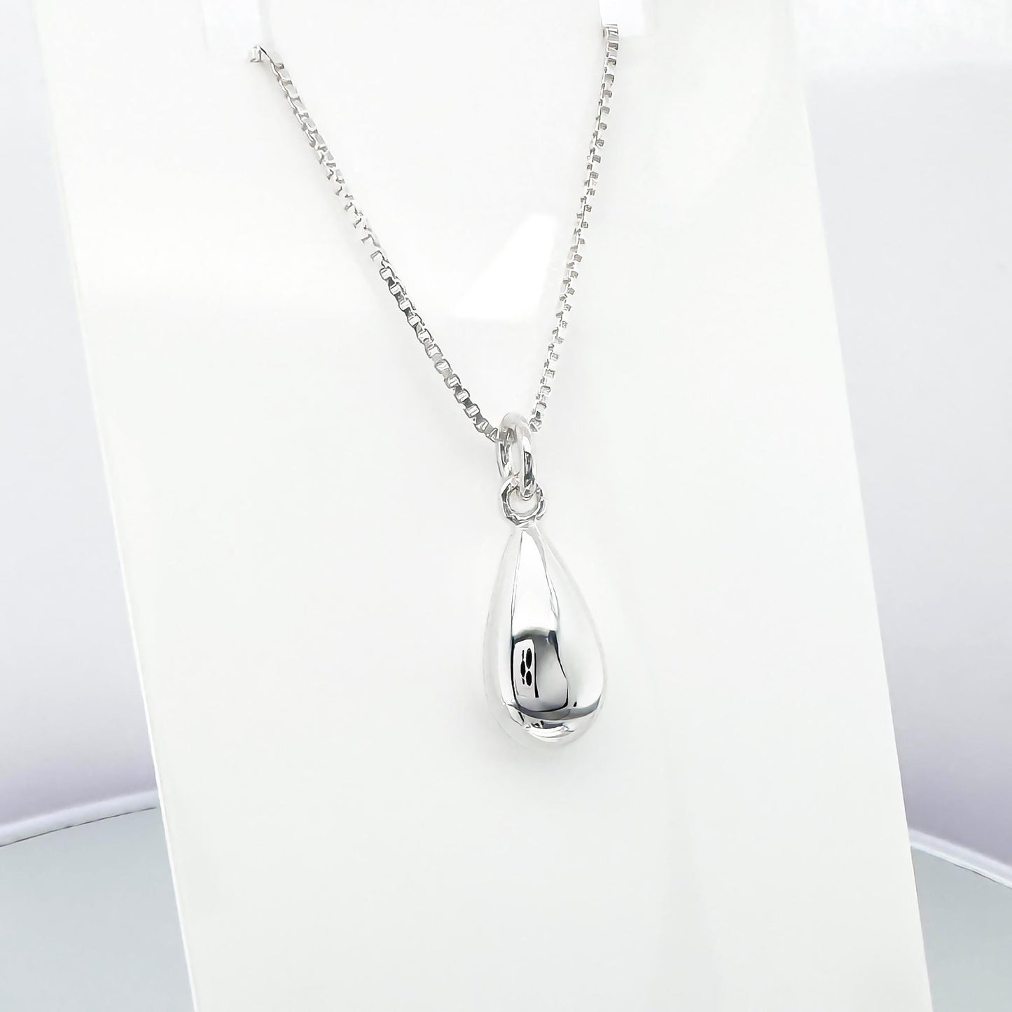A silver necklace with a pendant is displayed on a white background.