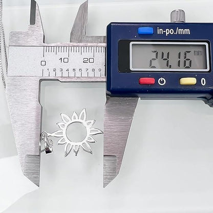 A digital caliper is measuring the size of a silver pendant with a flower design.