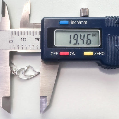 A digital caliper is being used to measure the size of a heart-shaped charm or necklace.