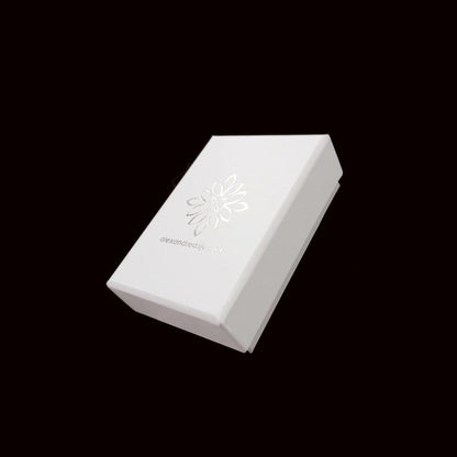 A white box with a silver flower design on it, set against a black background.