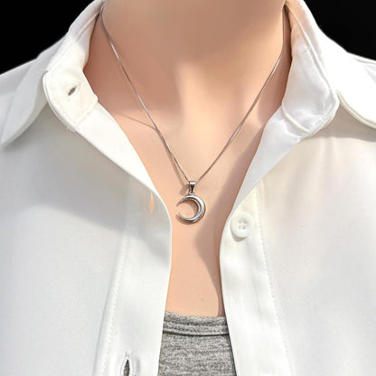 A close-up view of a person wearing a white collared shirt and a silver necklace with a pendant.