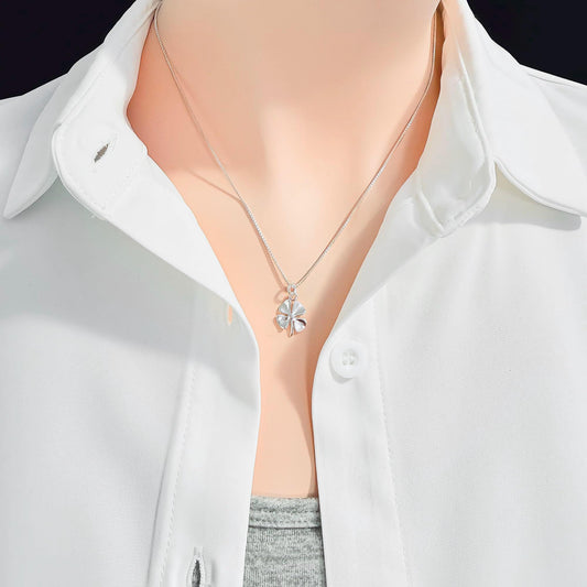 A close-up view of a person wearing a white collared shirt and a silver necklace with a small pendant.