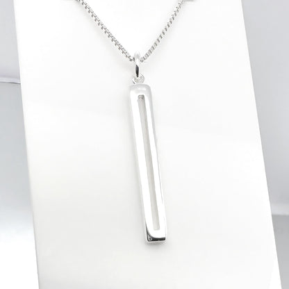 A silver necklace with a rectangular pendant is displayed against a white background.