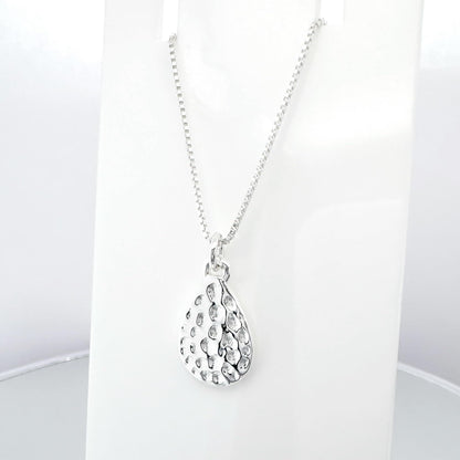 A silver necklace with a pendant featuring a pattern of small holes or dots.